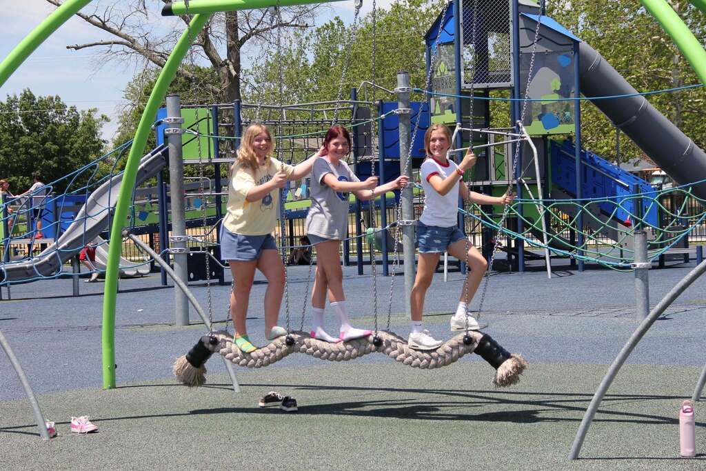 Three 5th grade girls smile for a photo on playground equipment