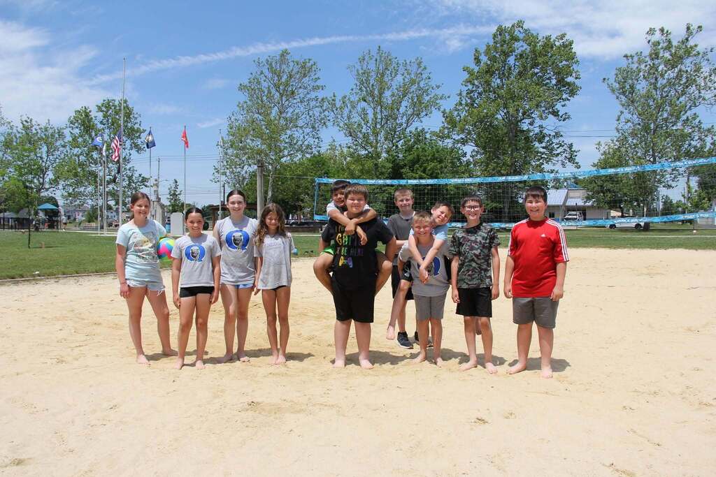 5th Graders smile on the sand volleyball court