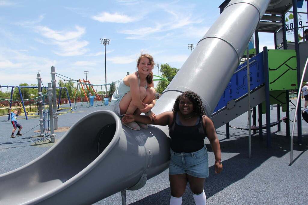 Two 5th grade girls smile for a photo on playgound equipment