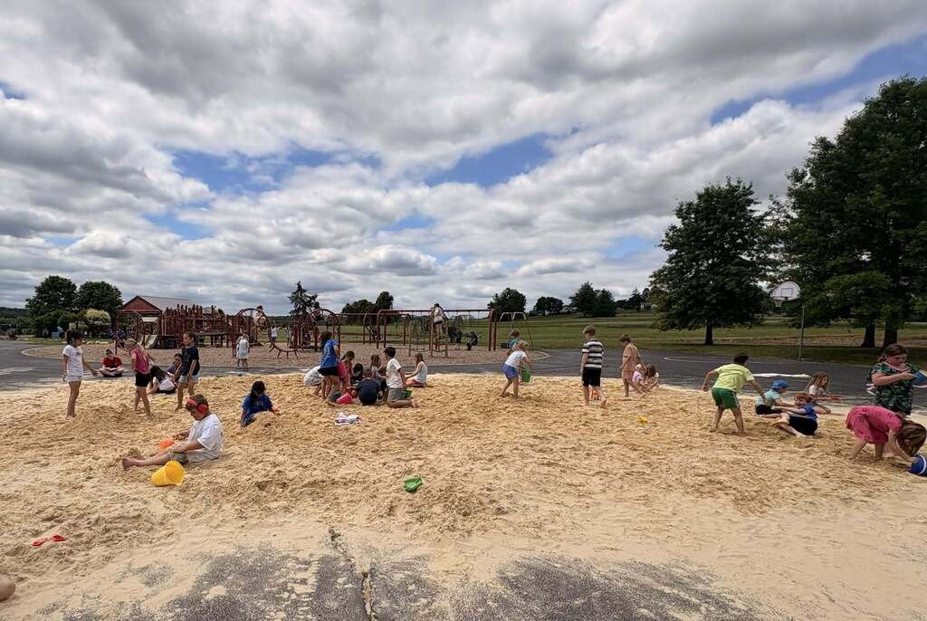 Students playing in the sand on their black top