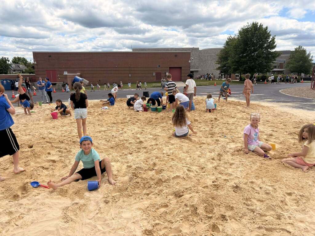 Students playing in the sand on their black top