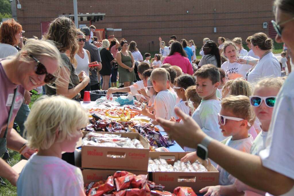 A table filled with snacks with adults on one side and students on the other