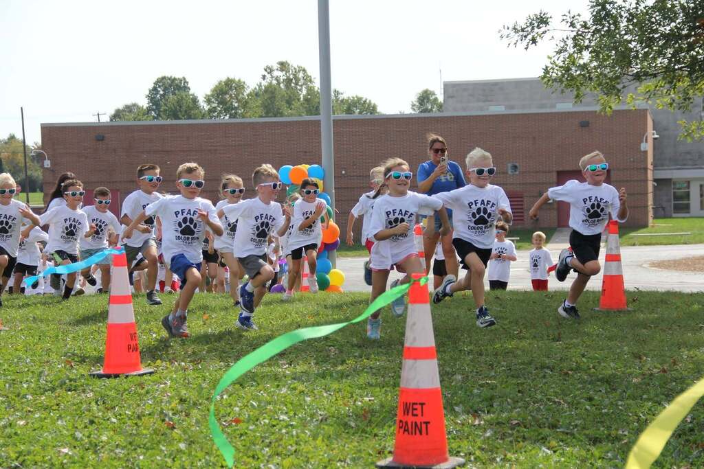 Children running up a grassy hill