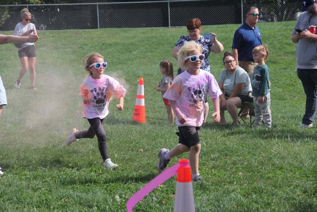 Children running on the grass and clouds of color chalk being splashed onto them