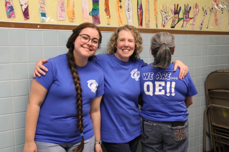 Former students smile with their "We Are QE" shirts on 