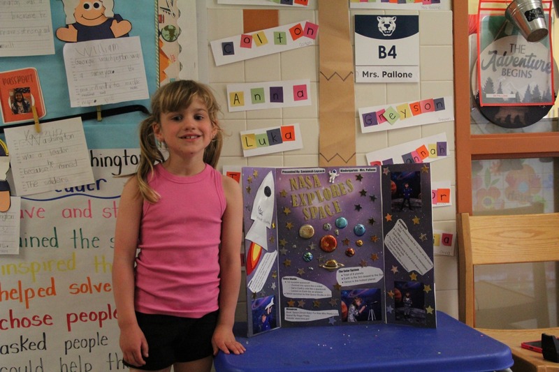 Student smiles with her presentation on space