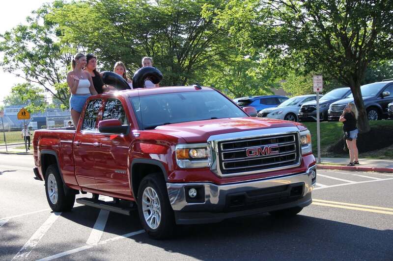 Students wave from the back of a pick up truck
