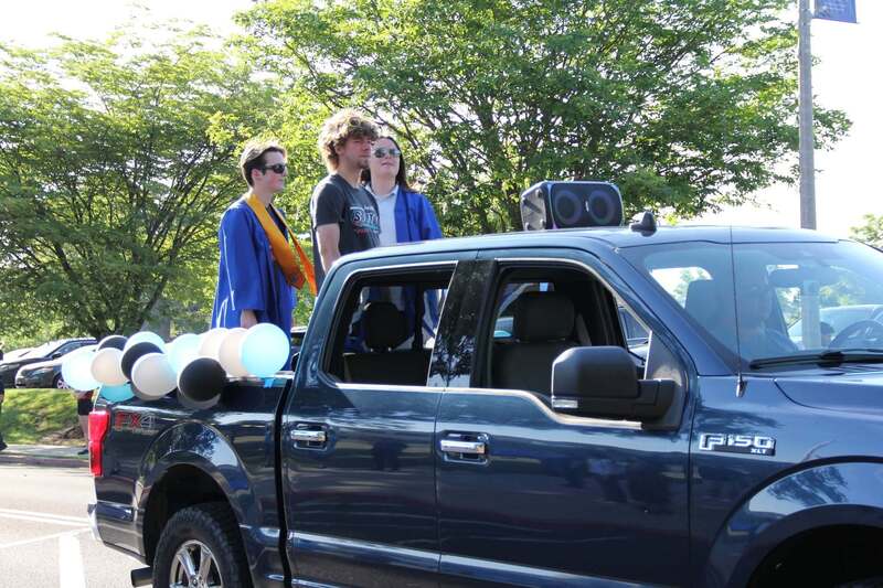 Students wave from the back of a pick up truck