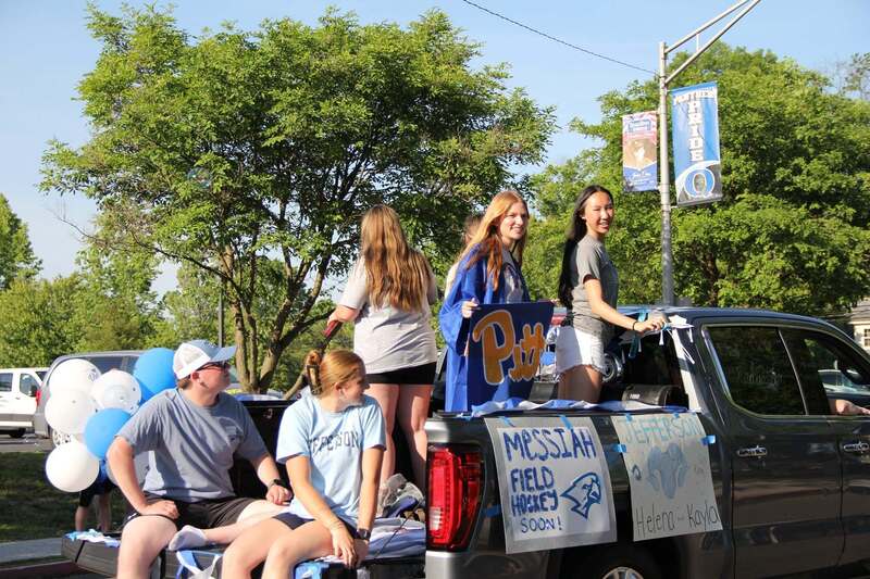 Students wave from the back of a pick up truck