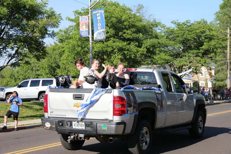Students wave from the back of a pick up truck