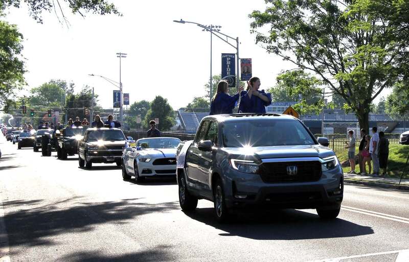 Cars drive down the street in a slow procession for the parade