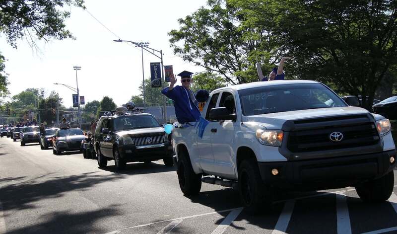 Students wave from the back of a pick up truck