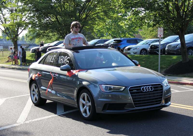 Student stands outside of a sunroof of a car