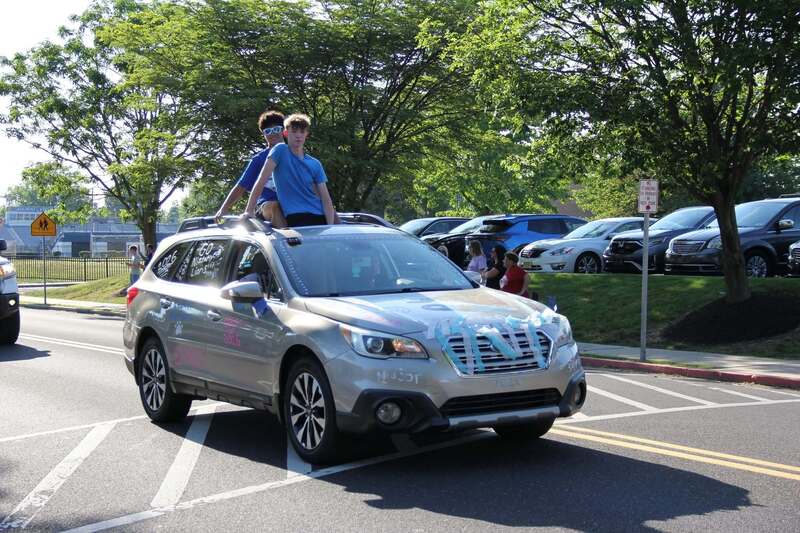 Students wave from the sun roof of a decorated car