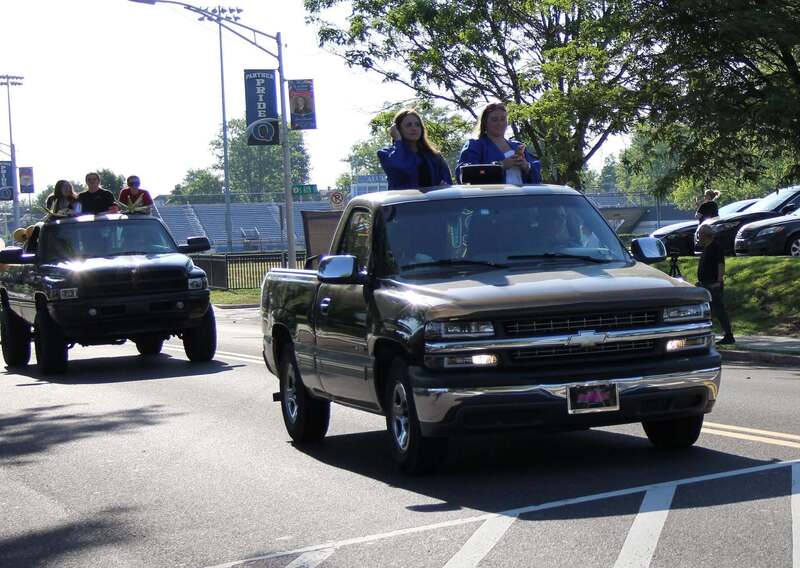 Students wave from the back of a pick up truck