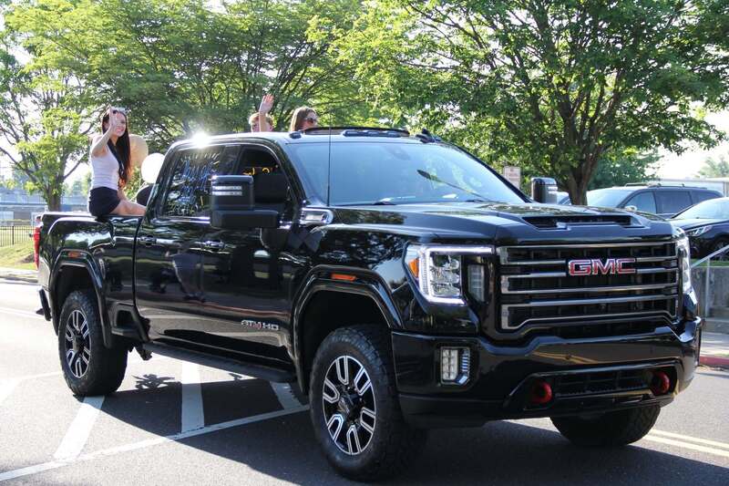 Students wave from the back of a pick up truck