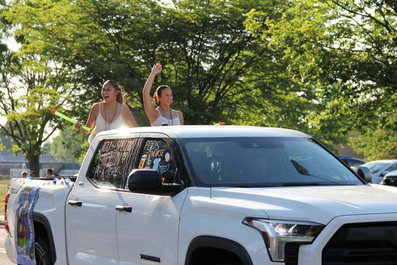 Students wave from the back of a pick up truck