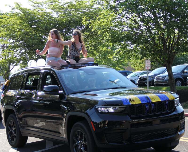 Students wave from the sun roof of their SUV