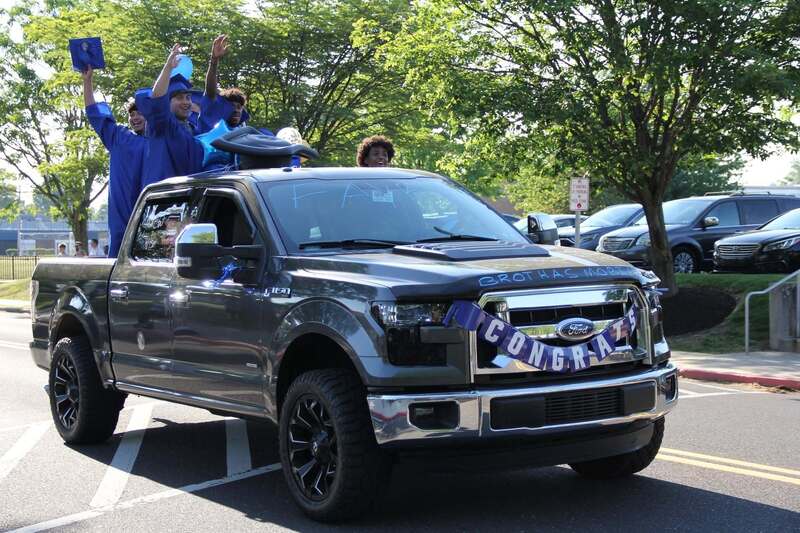 Students wave from the back of a pick up truck