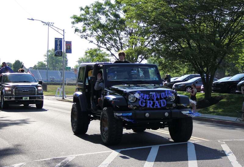 Student waves from the sun roof of a jeep