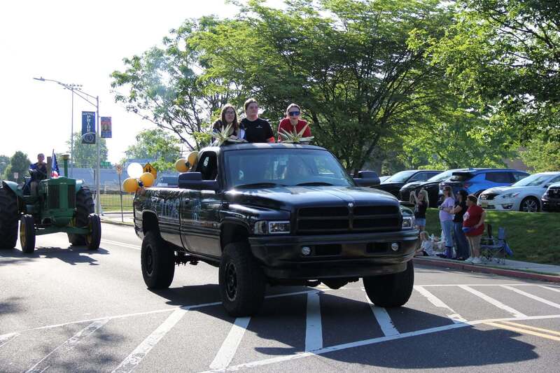 Students wave from the back of a pick up truck