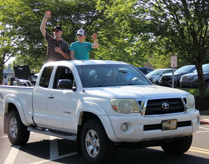 Students wave from the back of a pick up truck