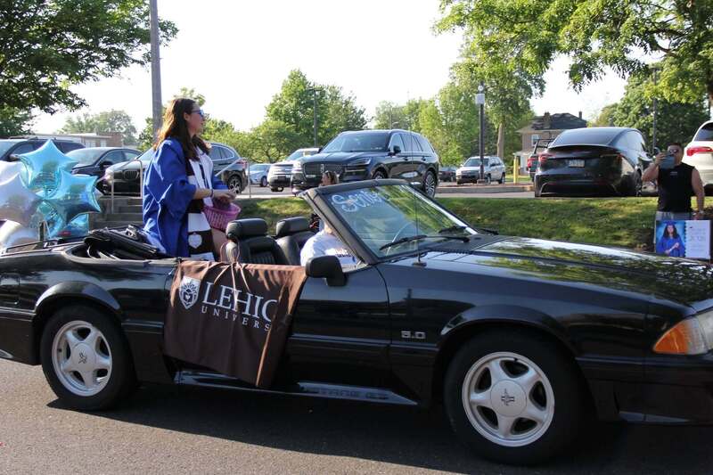 A student sits in the back of a convertible with a Lehigh University banner drapped on the side of the car