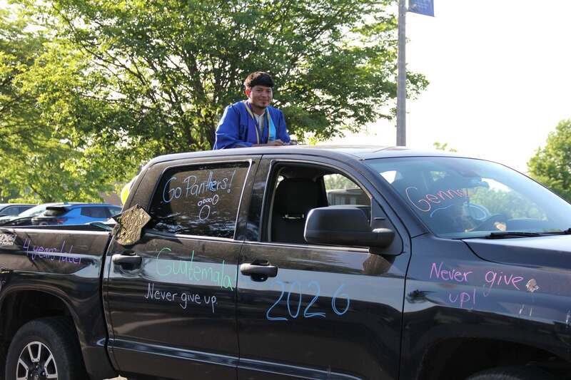 Students wave from the back of a pick up truck