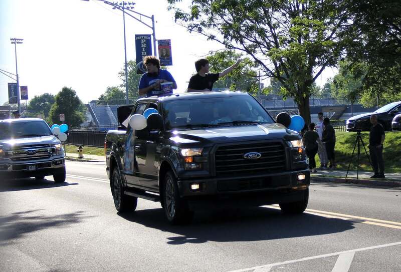 Students wave from the back of a pick up truck