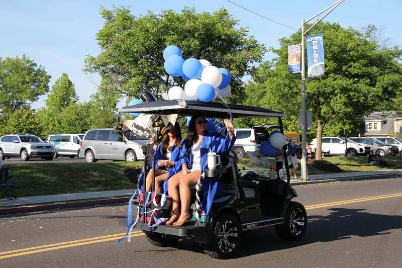 students sit in the back of a decorated golf cart