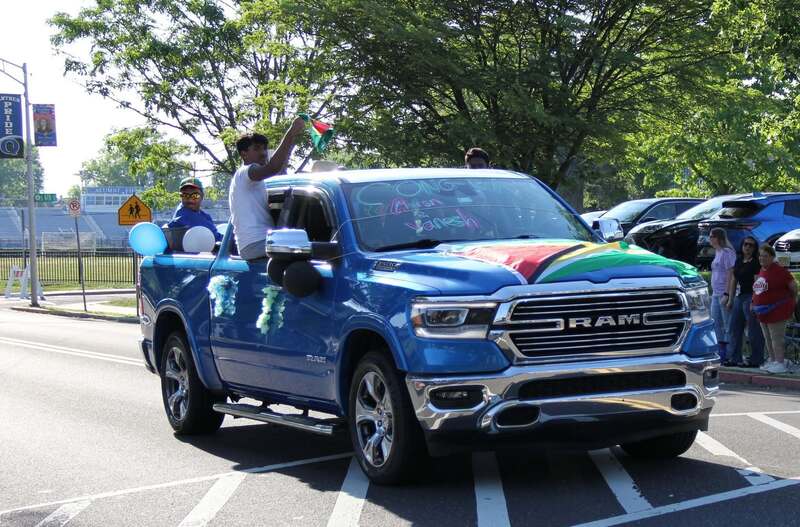 Students wave from the back of a pick up truck