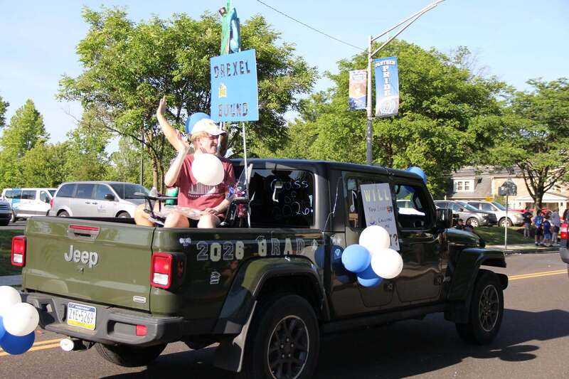 Students wave from the back of a pick up truck