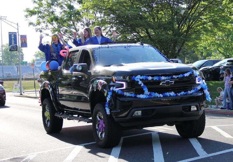 Students wave from the back of a pick up truck