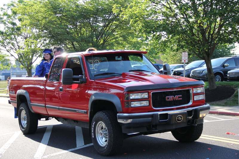 Students wave from the back of a pick up truck