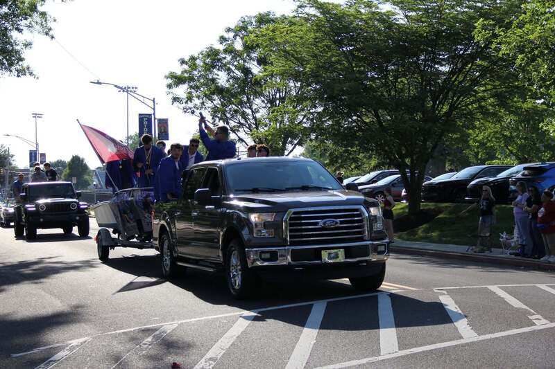 Students wave from the back of a pick up truck