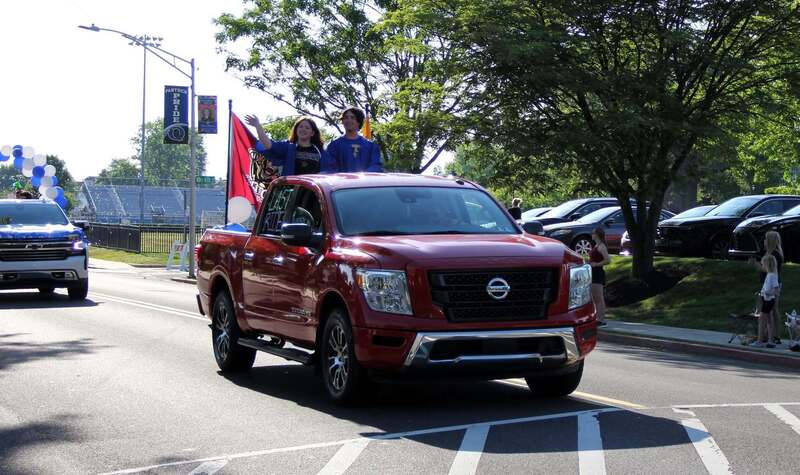 Students wave from the back of a pick up truck