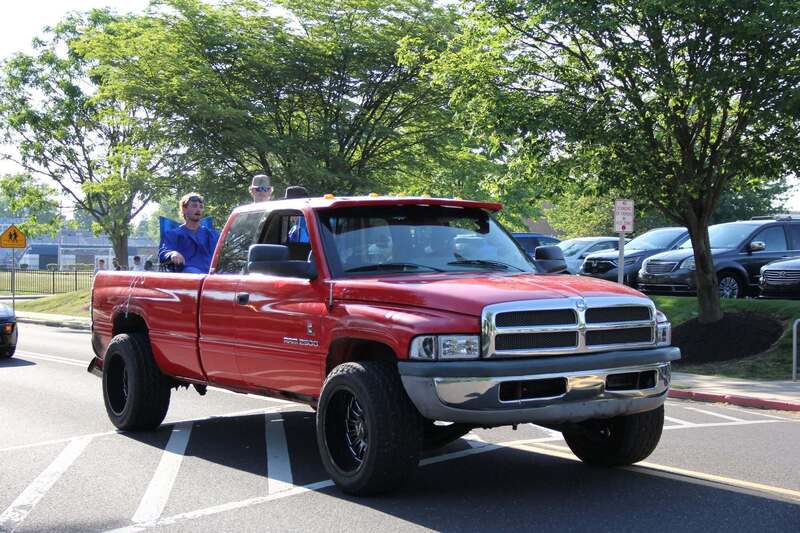Students wave from the back of a pick up truck