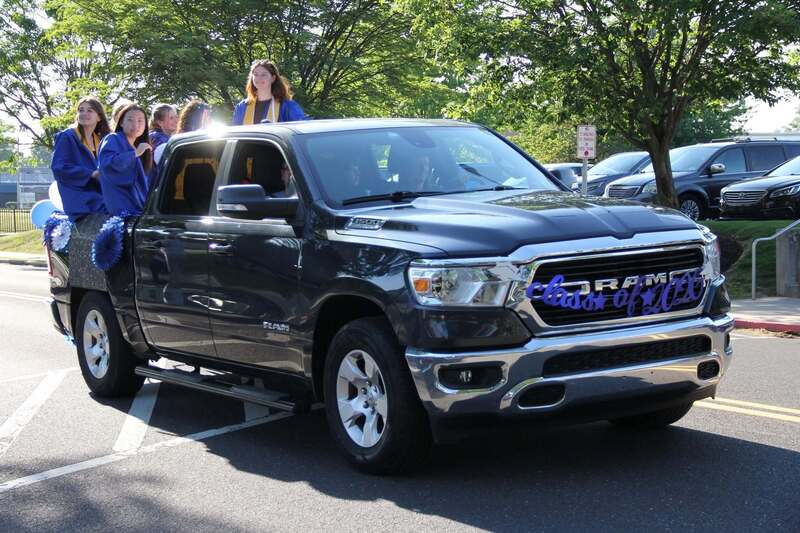 Students wave from the back of a pick up truck