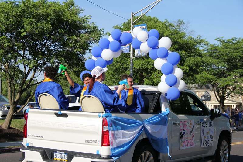 Students wave from the back of a pick up truck