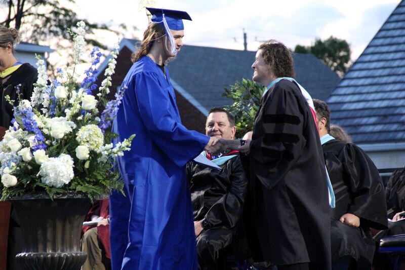 Dr. Hoffman shakes hands with graduates