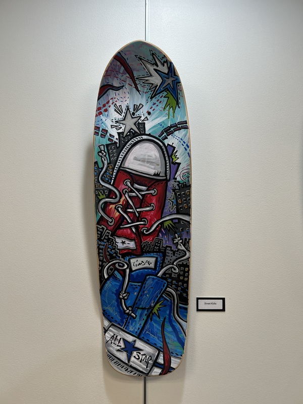 A skateboard deck with a painting of a red converse shoe