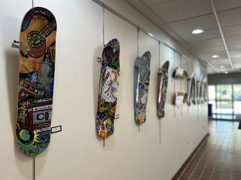 A photo of skateboard decks that are painted with images of radios, guitars and other lifestyle objects