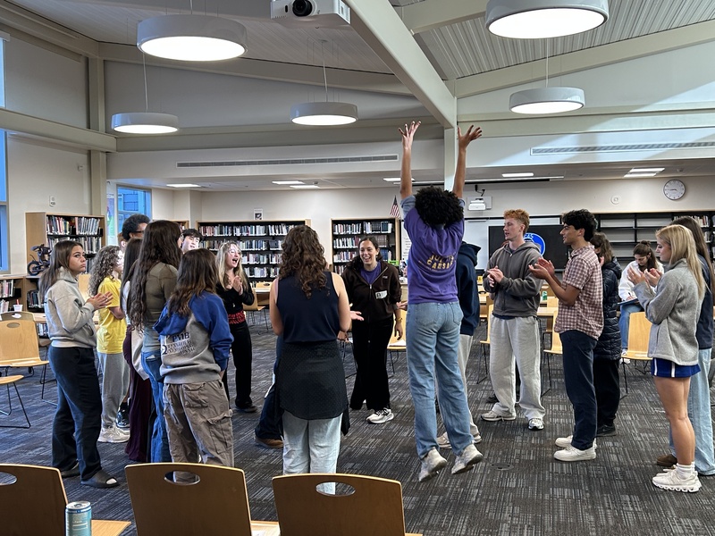 Instructor showing students how their body is their tool in theatre and leeps into the air