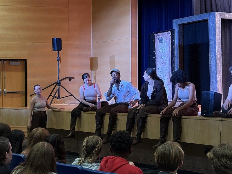 Students ask the actors questions as they sit at the front of the stage after the performance