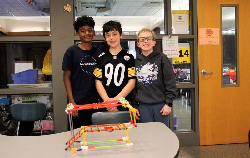 A Solar Charger - a box that charges batteries with Solar Panels Team: Aiden, Matthew, and Adrian / The Second Life Cells pose for a photo with their invention