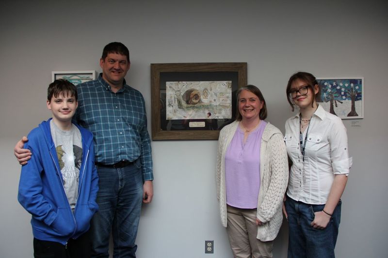 Ms. Clark's family smile with her artwork.