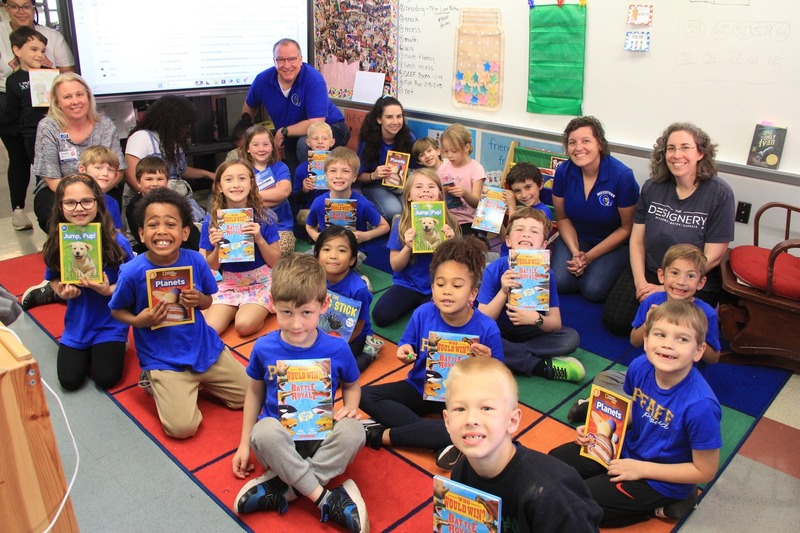 Students take a group photo and smile with their new books