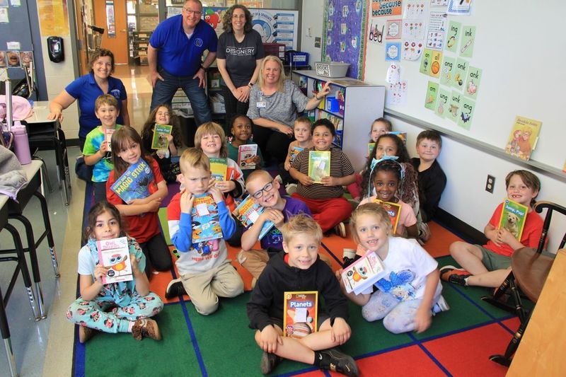 Students take a group photo and smile with their new books