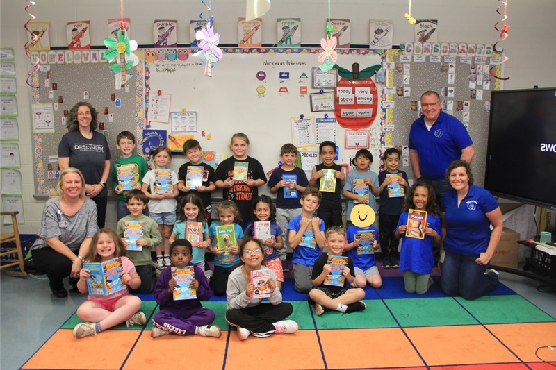 Students take a group photo and smile with their new books