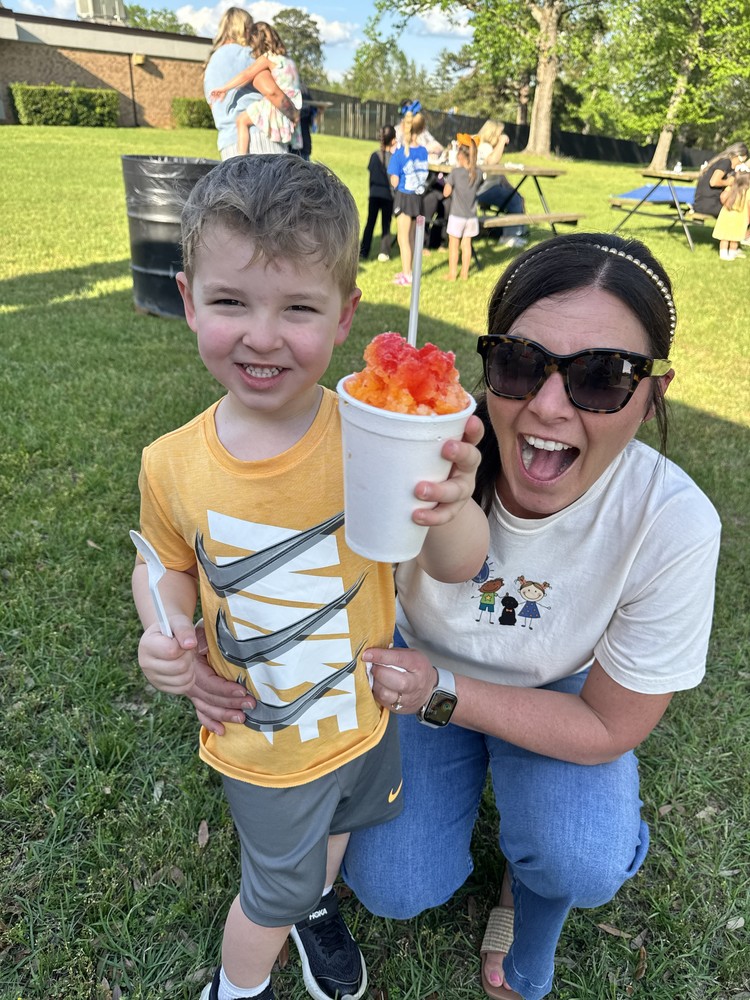 Principal Mrs. Stringer posing with a pre-K student and his sno-cone